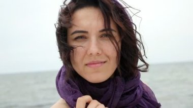 Kafasındaki bir menekşe pareo ile güzel bir kız bir sahil slo-mo closeup romantik bir esmer kız bir seabeach ayakta duruyor. O yaz slo-mo başına bir menekşe pareo ile gülümsüyor. Deniz harika görünüyor