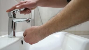 Orta yaşlı adam ağır çekim A heyecan verici closeup tuvaletinde orta yaşlı bir adam tarafından açılan bir paslanmaz çelik fauced paslanmaz çelik musluk altında ellerini yıkar. Çekimde streem altında ellerini yıkar