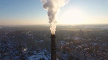 Hava bir kadeh beyaz duman karlı kış A kuş bakışı bir büyük kazan tüpün şehirde yoğun beyaz duman güneşli bir günde Ukrayna multistoried evlerde ile dev soğutma baca. Drone etrafında sinekler