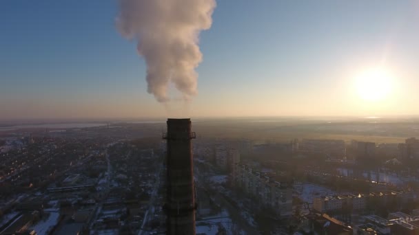Aerial shot of immense chimney with white smoke in snowy city at sunset in winter A bird`s eye view of a huge cooling tube with dense white smoke in multistoried buildings in Ukraine at sunset in winter — Stock Footage Aerial Shot Immense Chimney White Smoke Snowy City Sunset Winter Stock Video