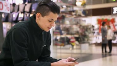 Akıllı bir adam bir akıllı telefon tutar ve onun perde bir havadar Mall profil başarılı genç adamın kim oturur ve bir akıllı telefon elinde tutar mürettebat saç kesimi ile dokunur. Sonbaharda bir alışveriş merkezi net sörf yapar