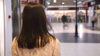 Şık kız gider, spin etrafında ve neşeyle yapılan ferah bir alışveriş merkezi etrafında döner bir neşeli seksi kız uzun bağsız kıl ile arka atış gülümsüyor ve gülümsüyor iyimser havadar bir alışveriş merkezi içinde.