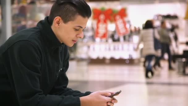 Молодой Человек Держит Смартфон Касается Экрана Современном Торговом Центре Профиль — стоковое видео