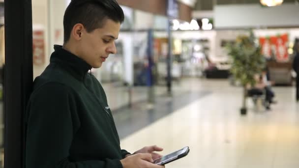 Mladý Muž Stojí Dívá Jeho Tablet Moderní Nákupní Centrum Podzim — Stock video