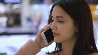 Bir süpermarkette bir cazibe ve ince genç kadın onun akıllı köpüklü shopwindows ve ürünler ile bir süpermarket içinde söz Closeup iyimser smartphone akıllı ve ince kız görüşmeler.