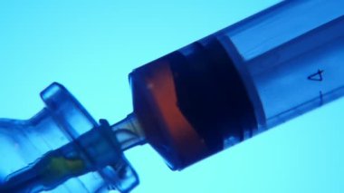 Kırmızı sıvı bir şırınga medial bir laboratuvar test tüp içine bir şırınga bir harika makro çekim kırmızı sıvı test tüpünden çarpık mavi arka planda alarak metalik bir iğne ile alınır.