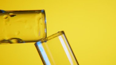 NET sıvı bir tüp iki laboratuvar tüpleri ile parlak yansıma bir makro çekim başka bir kimyasal laboratuvar içine dökülür. Sıvı bir test tüpünden sarı arka planda başka bir içine dökülür