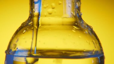 Tıbbi Laboratuar modern hacimsel şişeye sarı arka planda bir tıbbi laboratuvar yüklü büyük volumetric flask heyecan verici bir makro görünümü ile temiz sıvı dökülür. Berrak sıvı içinde dökülür.