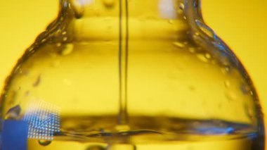 Tıbbi Laboratuar geniş hacimsel şişeye sarı arka planda bilimsel bir laboratuvar yüklü büyük volumetric flask etkileyici bir manzara ile şeffaf sıvı dökülür. Temiz sıvı içinde dökülür.