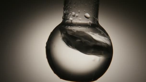 Crystaline 水与气泡在一个圆形的底部烧瓶震动在一个医疗实验室一个老式的宏观拍摄的清洁水在一个圆形的底部瓶在一个医疗实验室动摇 水用白色和灰色的影子玩耍 — 图库视频影像