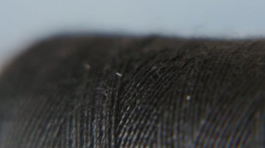 Siyah pamuk iplik ve bir iğne bir makara içinde bir siyah pamuk iplik makara dikiş için kullanılan uzun metal bir iğne ile retro bir makro içinde yavaş yavaş bir şık gri-mavi stüdyoda deldi bir gri-mavi stüdyoda deldi