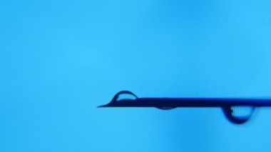 Bir damlacık su yatay bir iğne ucu üzerinde büyür ve bir laboratuarda düşüyor. İğne ucunda görünen su parlak bir blob muhteşem bir makro. Turkuaz bir laboratuvarda bir su akışı trinkles.