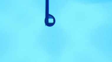 Su bir boncuk dikey bir iğne ucu üzerinde büyür ve bir laboratuarda aşağı gelir. Aydınlatılmış bir pencere içinde sahip su parlak bir blob soyut bir makro. Turkuaz aboratory içinde aşağı su kitapçık trinkles.