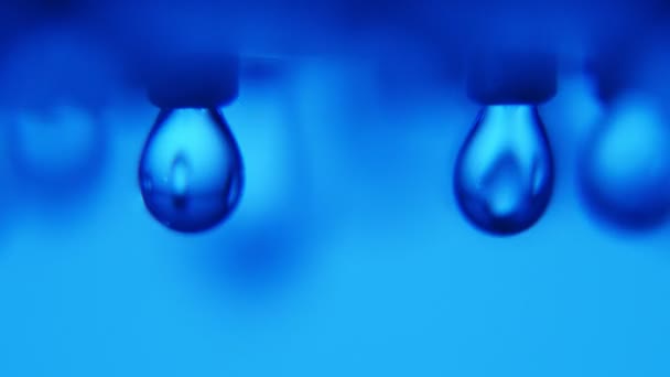 Des gouttes d'eau éblouissantes tombent d'un jet métallique dans une salle de bain bleue moderne Un plan macro inspirant de gouttelettes d'eau chatoyantes coulant d'une buse métallique dans une salle de bain arty aux murs bleus . 