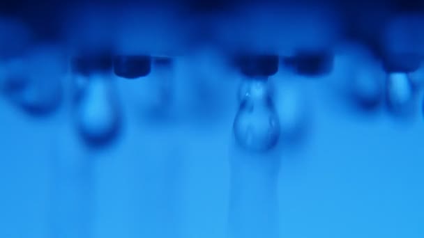 Čerstvé a čisté kapky vody padající z kovové jet v modré koupelně cheerul makro snímek křišťálově čisté kapky vody proudící z kovových trysek v moderní koupelně s modrými stěnami. 