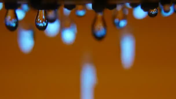 Brillantes bulles d'eau scintillant d'une buse métallique dans une salle de bain brune Un plan macro arty de gouttes d'eau cristallines relaxantes et coulant d'un jet métallique dans une douche moderne avec des murs bruns et dorés . 