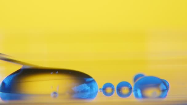斜针从实验室玻璃表面的一个小水坑中吸收水 Slimlike 金属针吸水晶透明液体的愉快的宏观在药房实验室与黄色墙壁的玻璃区域 — 图库视频影像