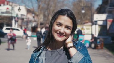 Neşeli ve mutlu bir kız gülümser bir sokakta güneşli bir yavaş hareket smartening ve neşeyle açık havada bahar yavaş çekimde gülümseyen uzun bağsız kıl ile şık ve başarılı genç kadın portresi