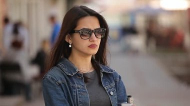 Şık kadın bir e-sigara içiyor ve duman bir sokak uzun bağsız kıl ve elektronik sigara sigara ve bahar beyaz duman dışarı nefes güneş gözlüğü olan zarif bir kadın portresi üzerinde bir sürü darbeler
