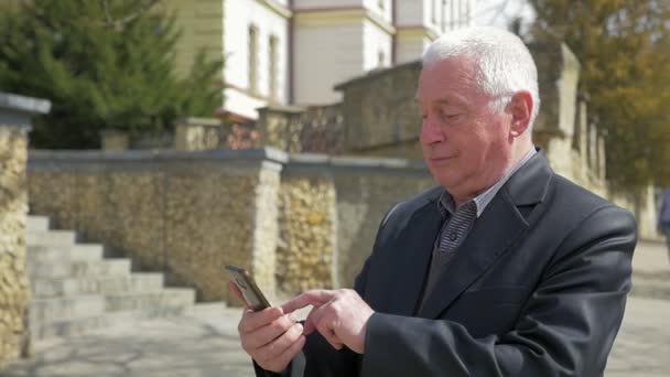 Homem Sênior Toca Tela Seu Telefone Uma Rua Primavera Câmera — Vídeo de Stock