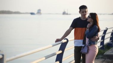 Şanslı adam bahar konuşuyor ve birbirlerine sarılma pitoresk Dnipro baharda çok güzel bir genç çifti portresi Dnipro iskele üzerinde güneş gözlüğü güzel bir kız sarılmak. Güneş gözlüğü ve pembe bir elbise kız.