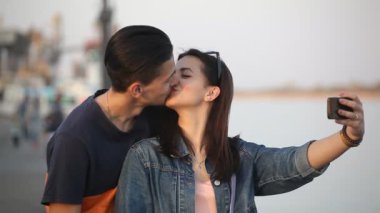 Romantik kız bir selfie alır ve Dnipro quay bahar yavaş çekimde Dnipro setin onun güzel tatlım kız öpüşme şanslı bir genç adam portresi slo-mo içinde onun adam öper. Bir aşk selfie alıyorlar 