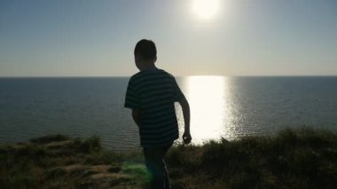 Mutlu çocuk bir harika gün batımı yavaş bir eğlenceli bir dokuz - yıl yaşlı erkek çocuk Karadeniz için gezinme ve sihirli slo-mo parlak güneş yolu ile batımını görünümünü geri yaz aylarında Karadeniz'e dolaşır