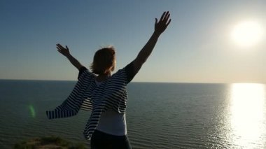 Mutlu kadın elleri kadar Karadeniz sahilinde slo-mo arka görünümünde bir donanma singlet ve mutlu bir şekilde ellerini yükselterek ve günbatımı slo-mo yaz aylarında muhteşem bir yolda bakarak pareo içinde neşeli bir kadın gün batımında yükseltir