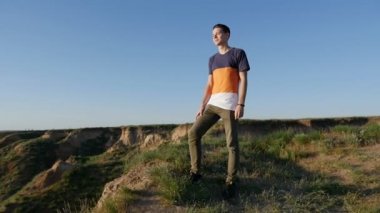 Şık genç adam görünüyor ileri slo-mo profilinde bir T-shirt Karadeniz sahilinde ayakta ve ısmarlayarak slo-mo yaz aylarında zevk içinde mürettebat saç kesimi ile neşeli bir genç adamın, Karadeniz kıyısında duruyor