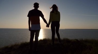 Aşık bir çift yaz arka görünümü yakınlaştırmak romantik bir adamın parlayan güneş yolu ile muhteşem bir günbatımı, Karadeniz onun kız arkadaşı el tutmak ile Karadeniz sahilinde bir arty günbatımı keyfini