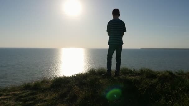 兴奋的男孩看着风景如画的太阳路在日落在夏天在慢动作一个九岁的男孩站在黑海 看着灿烂的日落与灿烂的太阳路径斯洛伐克 — 图库视频影像