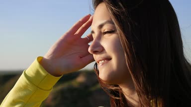 Mutlu kız gülümsüyor, smartens ve bir cheeryl kızın slo-mo profilde Karadeniz kıyısında uzun bağsız kıl Karadeniz dalgaları seyir ile saç sırayla koyarak yaz slo-mo gün batımında gülümseyen görünüyor