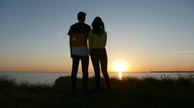 Mutlu çocuk ve kız Karadeniz sahilinde stand ve güneşin batışını slo-mo birkaç içinde aşkın Karadeniz kıyısında birbirlerinin ellerini tutarak ve güneş yolu ile yaz aylarında batımını şaşırtıcı bir görünümü