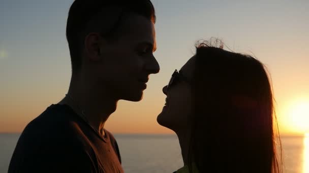 微笑的女孩和她的快乐的男孩站在黑海海岸的夕阳在夏季的一个多情的情侣看着对方 并愉快地微笑着在海边的海滩上风景如画的日落夏天 — 图库视频影像