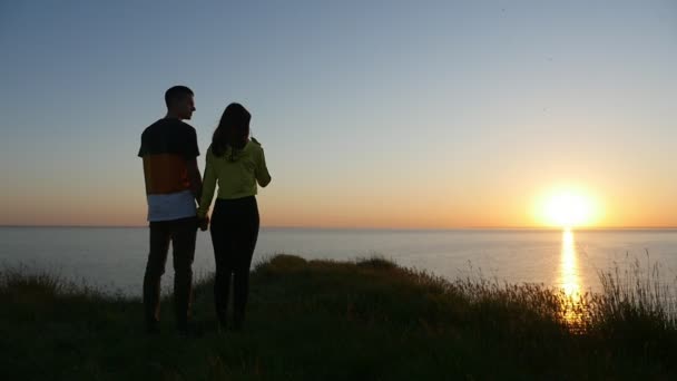 多情的男孩和女孩站立和谈话在黑海海岸在日落在斯洛伐克 一个美好的看法一对夫妇在爱保持彼此的手和谈论在日落的黑海海岸与太阳路在夏天 — 图库视频影像