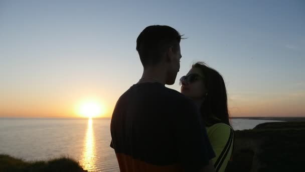 可爱的女孩和她的激情的男朋友在黑海海岸日落在夏天一个美妙的看法一对在爱拥抱和看彼此在日落与金黄太阳路径在黑海海岸在夏天 — 图库视频影像