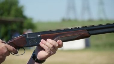 Adam bir skeet aralığını yazın yavaş çekimde bir avcı onun üzerinde ve altında çift namlulu shortgun yükselterek ve çekimde çekim profil silahıyla pratiği yapıyor. Shortgun geri tepme güneşli bir günde sallıyor..