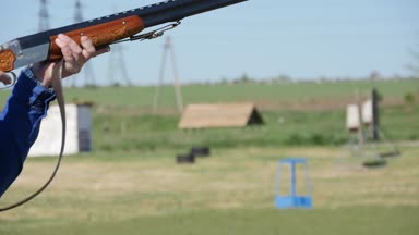 Avcı bir skeet aralığını yazın yavaş hareket profil hedef arayan ve çekimde çekim onun shortgun yükselterek bir pro insanın onun shortgun ile eğitiyor. Shortgun geri tepme güneşli bir günde sarsıntıları..