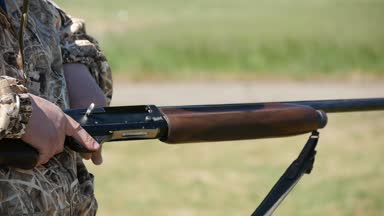 Onun tek namlulu shortgun makat kartuş ile yükleme, makat kapanış ve yavaş hareket yaz aylarında üzerinde yeşil bir aralığı hedefleme bir sporcu slo-mo Closeup aralığında tarih makat yükleme Tüfekçi