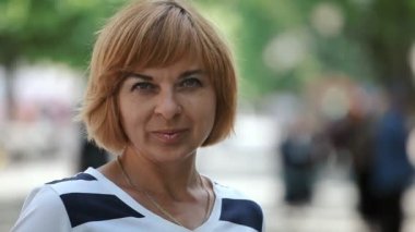 Romantik sarışın kadın standları ve gülümsüyor yeşil bir arka sokakta güneşli bir günde bir siyah ve beyaz bluz ayakta ve obscurities gülümseyen bir parkta yaz aylarında bob saç modeli ile zarif bir sarışın kadın portresi