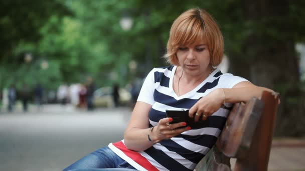 성급한 여자와 여름에 화창한 공원에서 그녀의 스마트폰에 그물을 헤어스타일으로 자신감 — 비디오