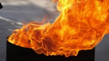 Yazın siyah bir küvetin üzerinde çatal oynayan parlak kırmızı ve sarı alevler. Yazın açık havada duran siyah bir tencerenin üzerinde dönen kırmızı, sarı ve turuncu ateş dillerini hayret verici bir şekilde gösteriyor. Gizemli, etkileyici ve iyi görünüyor..