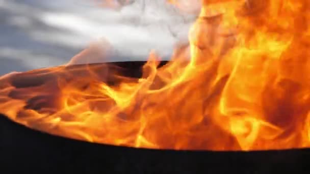 Feu rouge et jaune vif avec fourchettes sur un réservoir noir à l'extérieur en été Vue imprenable sur les langues de jeu de feu rouge, jaune et orange tournant sur un pot noir placé à l'extérieur en été. Il a l'air magique, impressionnant et agréable .