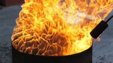 Alev püskürtücü başlığıyla siyah bir küvetin üzerinde tehlikeli bir yangın. Dışarıdaki siyah bir tencerenin üzerine yükselen yoğun ateş dillerinin sihirli görüntüsü. Hortumlu siyah bir alev püskürtücü bir ateş akışını yönlendiriyor..