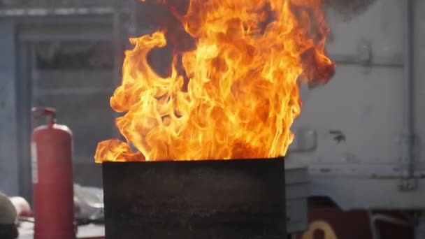 大きな鍋にバケツから液体を注ぎ男性の手はバケツを保持し 遅い動きで夏に屋外の大きな鍋の上に上昇する高炎にいくつかの液体を注ぐ男性の手の壮大な景色 — ストック動画