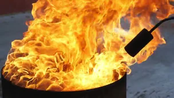 火の流れを目指す火炎放射ノズル付きの黒い鍋の上に熱い炎屋外に置かれた黒い浴槽の上に立ち上がる高密度の火の舌の印象的な眺め その中に火の流れを目的としたノズルを持ついくつかの黒い火炎放射器 — ストック動画