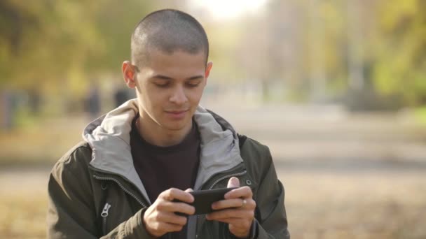 Smiling Young Man Standing Park Browsing Net Autumn Slow Motion — Stock Video