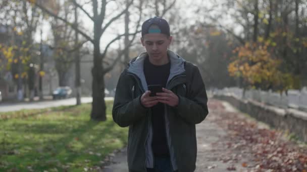 Joven Inteligente Caminando Parque Navegando Por Red Otoño Cámara Lenta — Vídeos de Stock