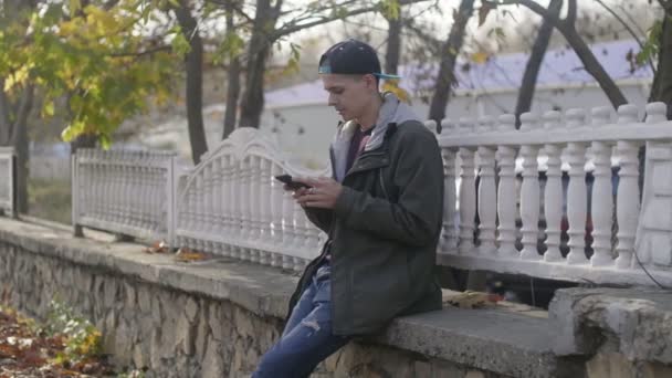 Smart Young Man Sitting Stone Parapet Browsing Net Autumn Υπέροχη — Αρχείο Βίντεο