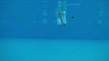 Güneşli bir günde, güneşli bir günde, ilk kez havuza dalan mutlu genç, uzun şortlu, neşeli ve sportif bir gencin güneşli bir yaz gününde, mavi sularla dolu bir gölete ilk kez dalışının komik görüntüsü..